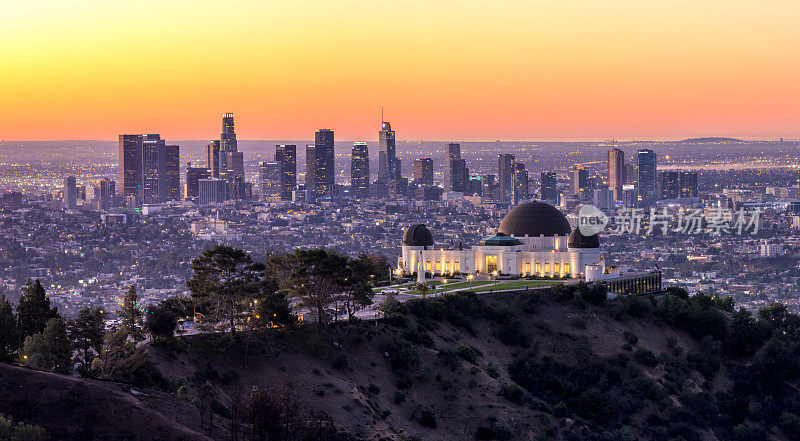 洛杉矶天际线在日出全景和格里菲斯公园天文台在前景。加州。美国