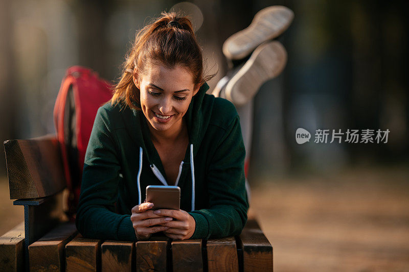 漂亮的年轻运动女性与智能手机在户外