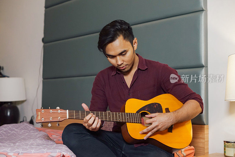 亚洲年轻人在卧室里弹吉他