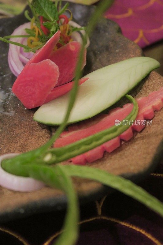 艺术沙拉配菜，胡萝卜花和叶子，黄瓜叶，切成花的辣椒，红洋葱片作为篮子的辣椒和薄荷在印度餐厅晚餐的照片