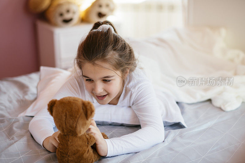 漂亮女孩和她的泰迪熊在床上