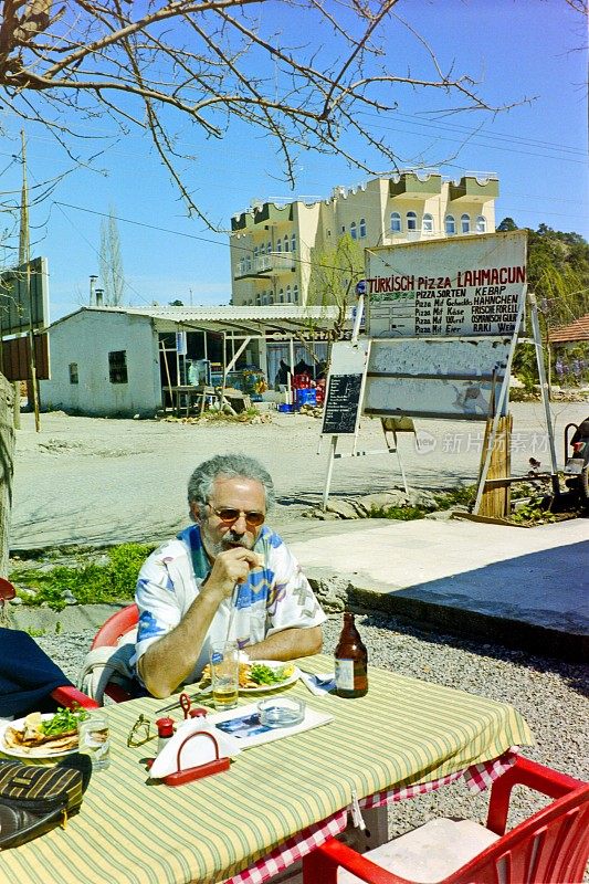 土耳其里维埃拉1998年的今天，一名游客在土耳其Beldibi附近的一家街头餐馆享用他的午餐。
