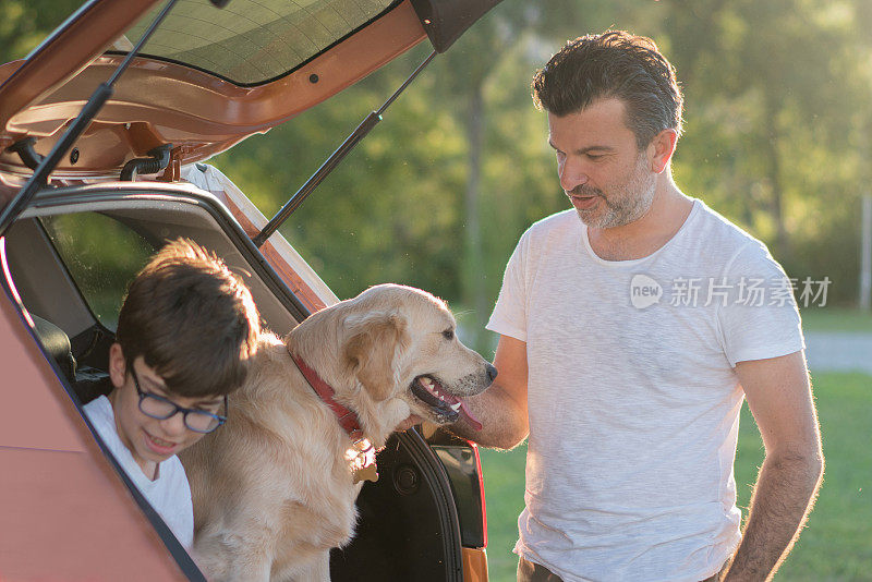 父子俩带着金毛猎犬一起上了汽车的后备箱