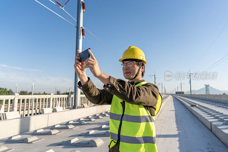 一名亚洲男性工程师在尚未完工的高速公路上用手机拍照