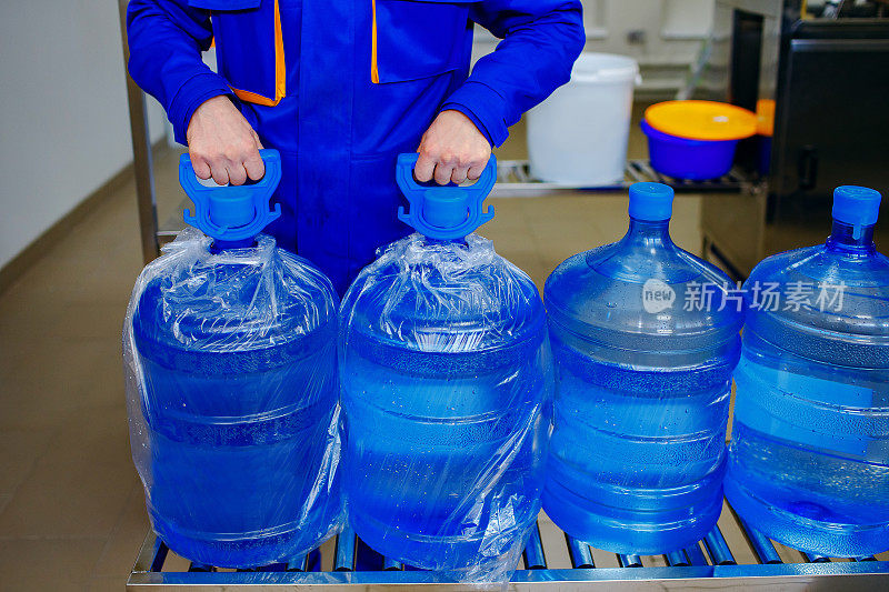 纯净水厂，一名男装载工戴着大瓶干净的饮用水