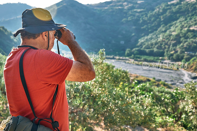 游客用双筒望远镜看山景。背包旅行或户外运动。积极的人，远足，健康的生活方式和和谐的理念。与自然统一。