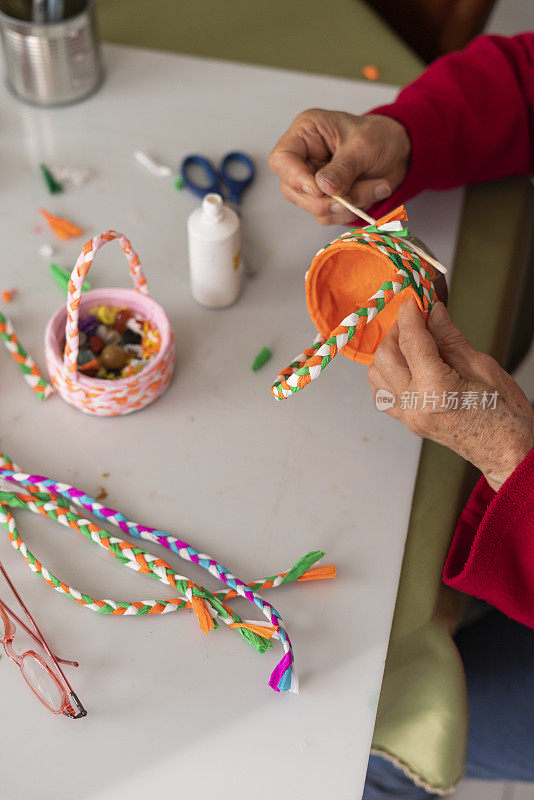 一位老妇人的手正在用材料制作工艺品