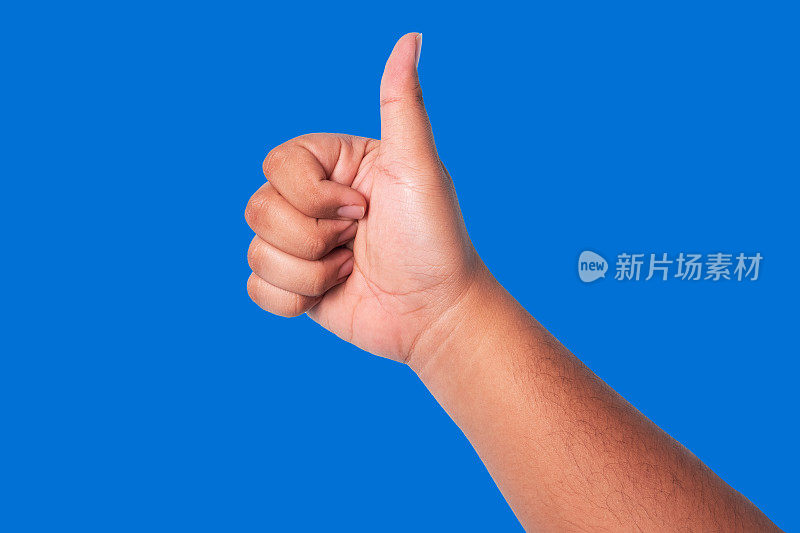 人的手竖起大拇指，概念表现出良好的欣赏，okay或agree，孤立在蓝色背景上
