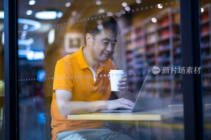 亚洲成熟男子在咖啡店使用笔记本电脑