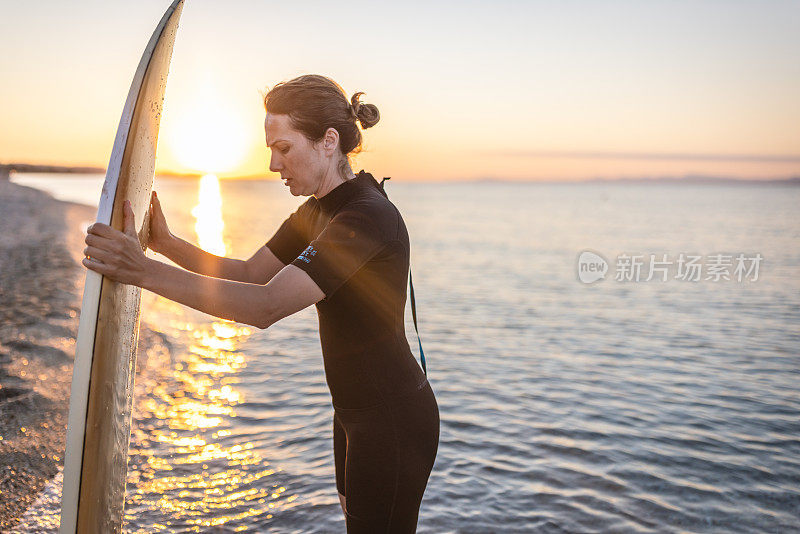 一个拿着冲浪板站在沙滩上的女人