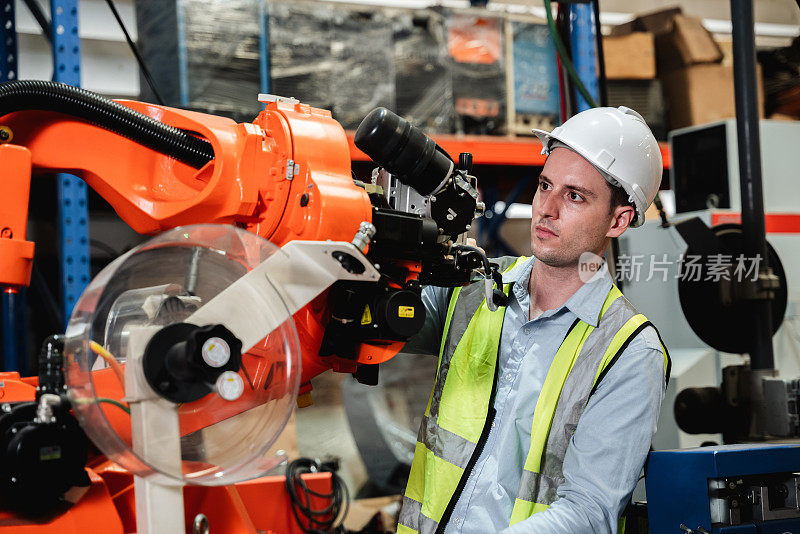 工业工程师在工业制造工厂控制自动臂机焊接机器人。