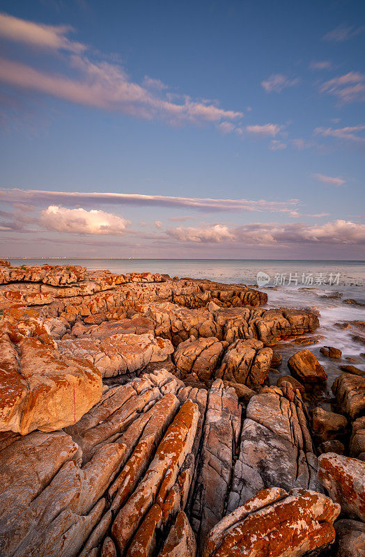 在南非开普敦外的开普半岛的福斯湾，鱼虎克的岩石海岸线上的海浪与充满活力的日落
