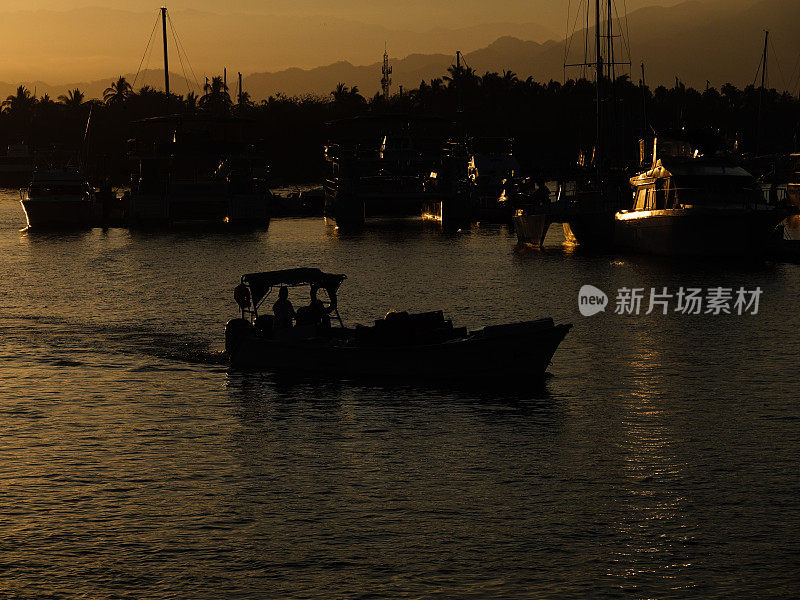 日出时，一艘小船和一个男人的剪影缓缓驶过码头。