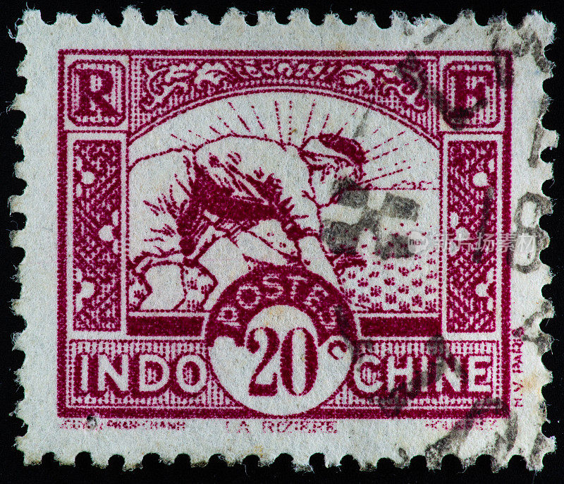 在一张法属印度支那的旧邮票上，田里的工人弯腰收割水稻。