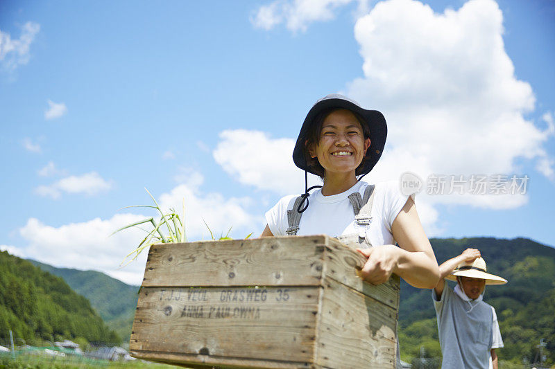 微笑的女人拿着一个装满蔬菜的木箱