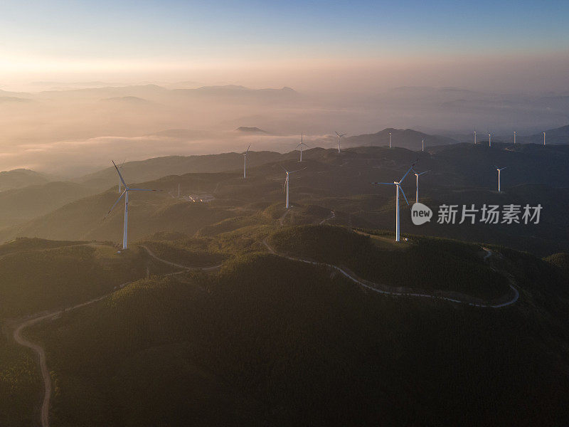 太阳照在山上的整排风力涡轮机上