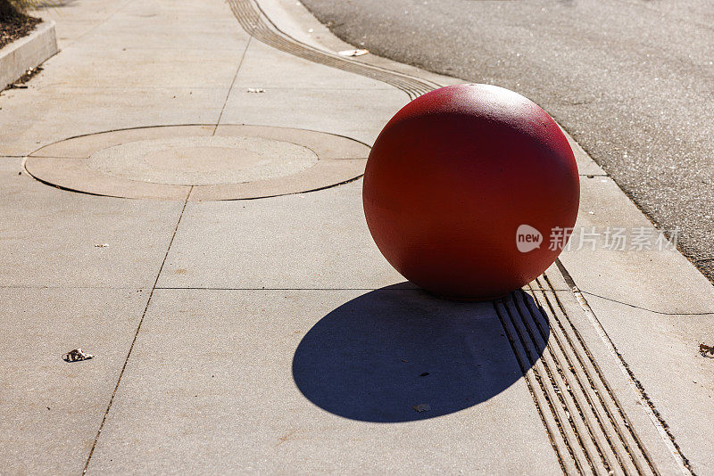 红色的，混凝土球带着影子，沿着路走。