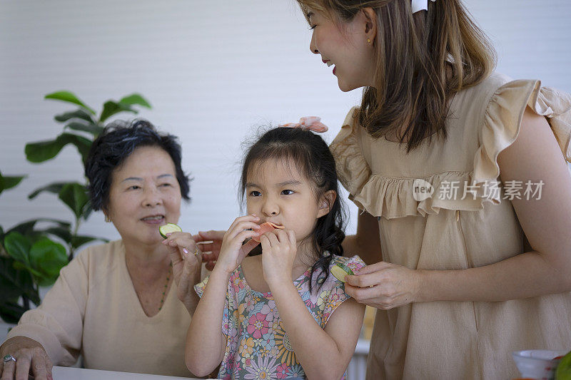 奶奶、妈妈和孙女在厨房准备食物。