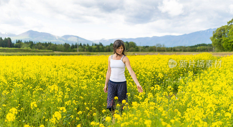 一位妇女在一片黄色的油菜花地里放松和享受户外活动