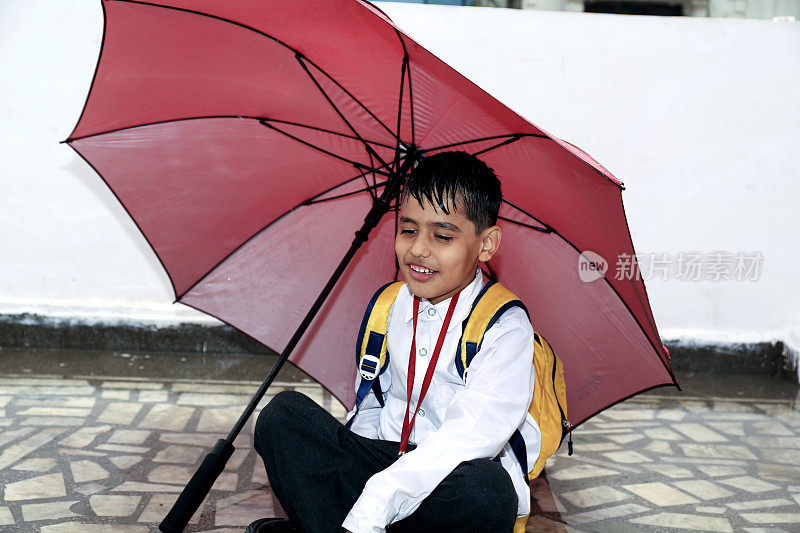 雨季，小学生在家里拿伞的照片