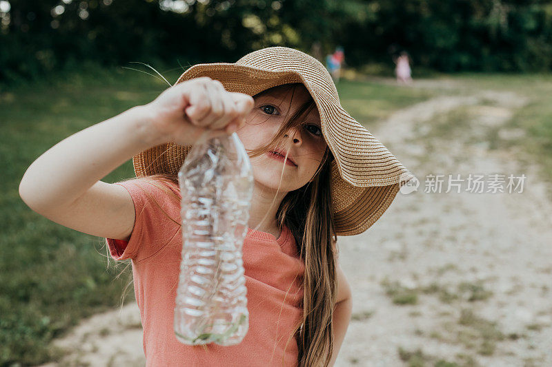 小女孩在户外夏令营玩耍时用水瓶抓虫子