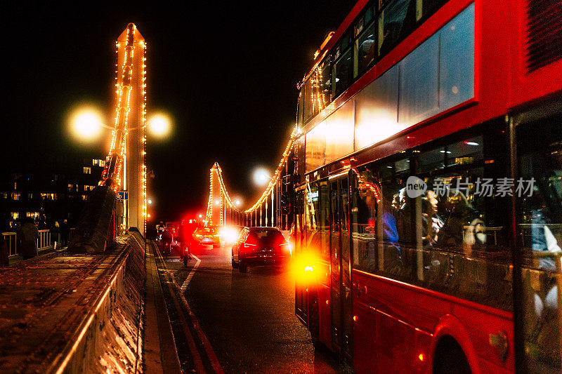 英国伦敦市中心夜间，一辆双层巴士行驶在灯火通明的切尔西桥上