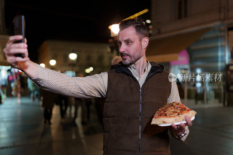 男子在城市灯光下品尝披萨