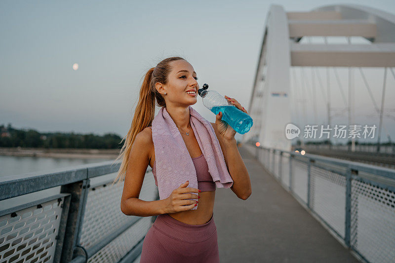 年轻女子跑完桥后喝水