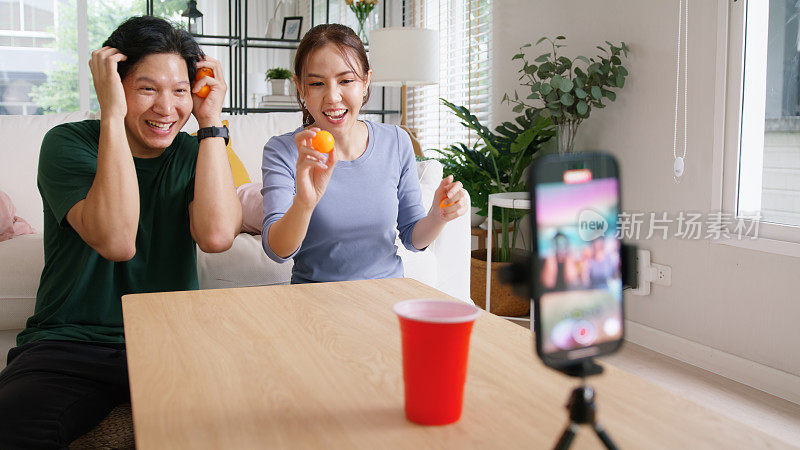 成人影响者youtuber亚洲人视频博主记录病毒视频视频博主页面直播有趣的游戏啤酒乒乓球扔杯子IG卷轴instagram抖音社交媒体时髦的快乐为年轻夫妇的副业。