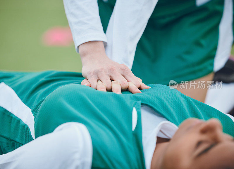 事故发生后，一名曲棍球运动员在球场上用手、急救和心肺复苏术拯救她的队友。一个女人在草地上帮助她的朋友，健身，心脏病和紧急发作