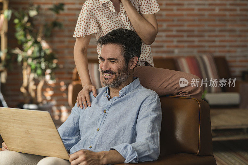 一个成熟的男人坐在扶手椅上检查他的储蓄和婚姻财产，高兴地和妻子一起赚利息