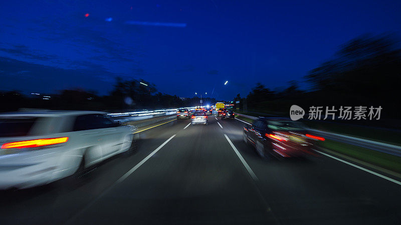 汽车行驶在灯火通明的夜间高速公路上。汽车视角