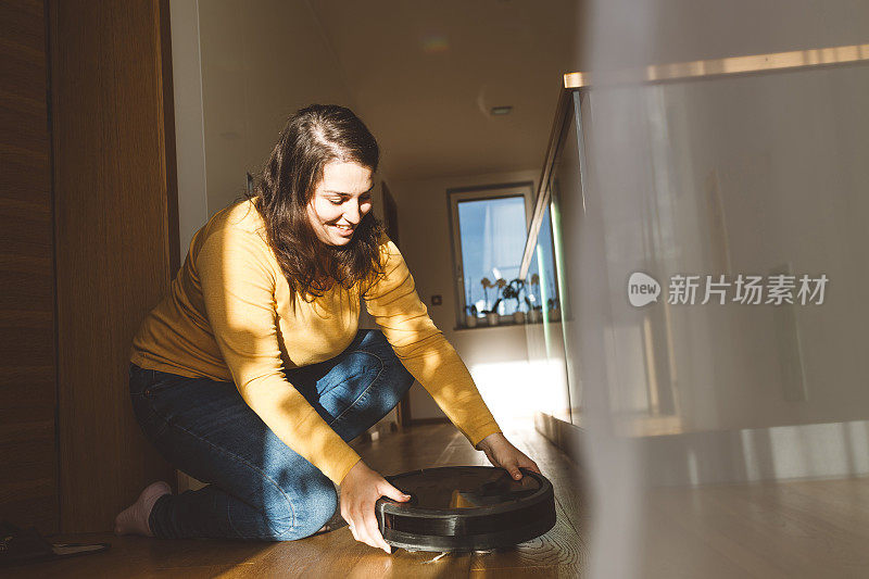 一位女士用平板电脑控制机器人真空吸尘器