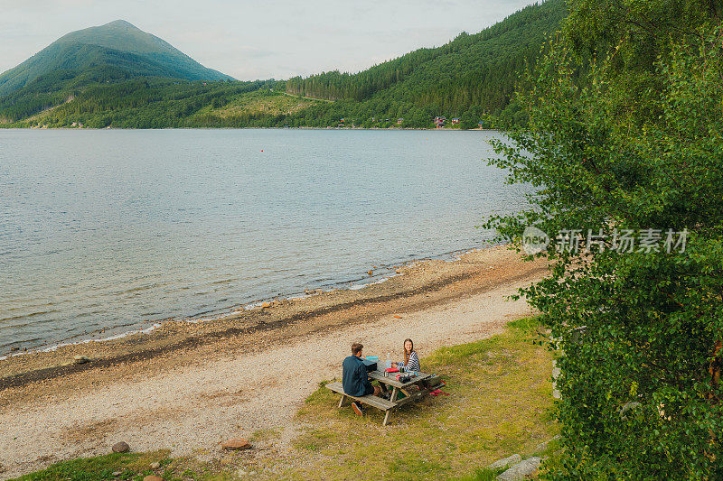 鸟瞰图的女人和男人欣赏野餐的湖与山景