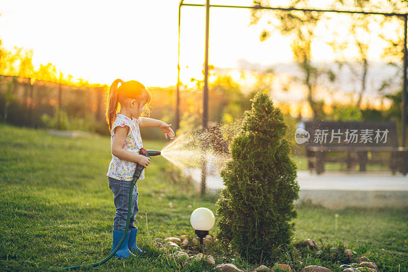 小女孩拿着水管给她的植物浇水