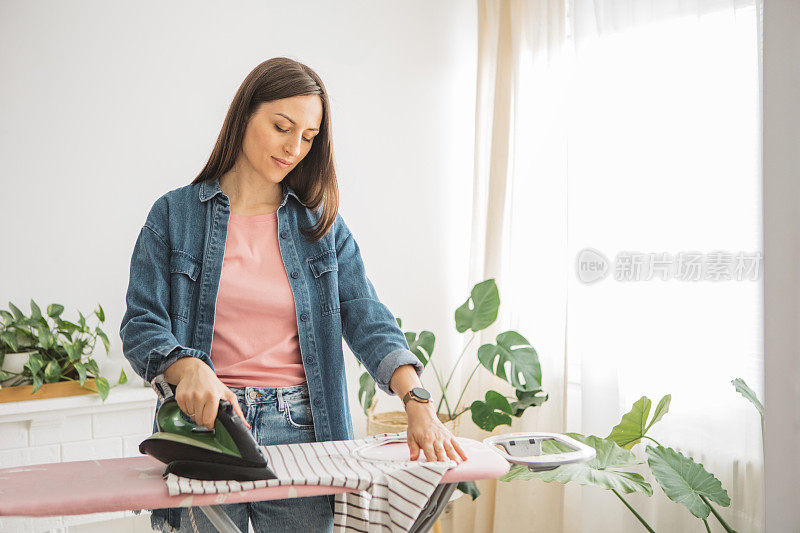 快乐的女人在家里熨衣服