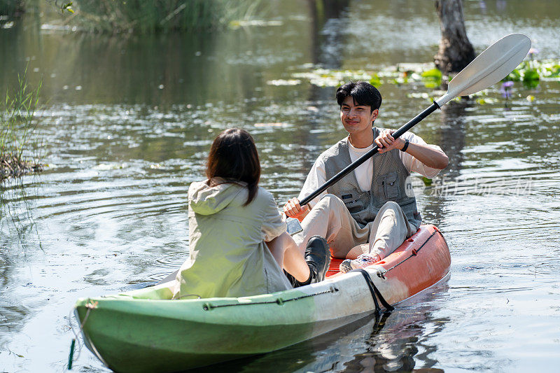 亚洲迷人浪漫的年轻夫妇划船在森林湖。背包客男女旅行和皮划艇在美丽的红树林享受一起度过假期的时间。