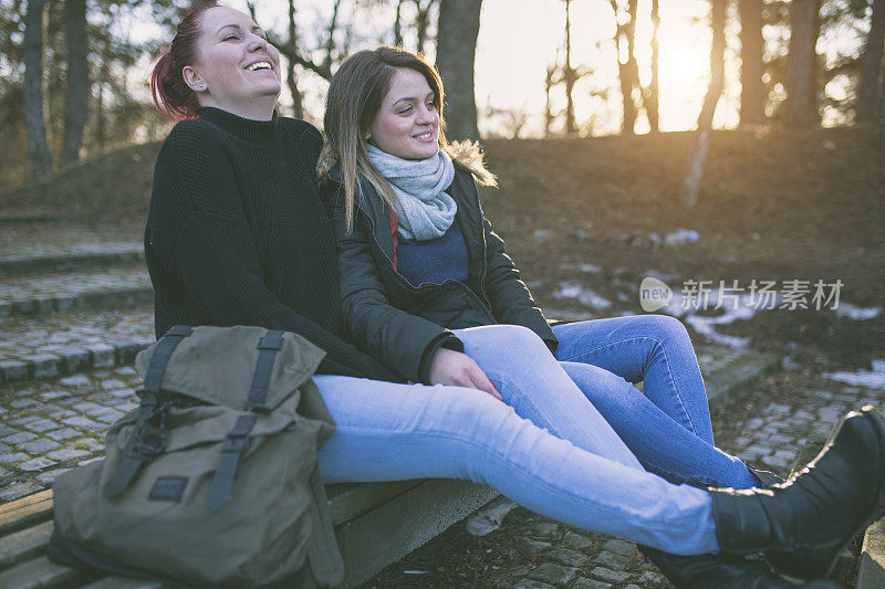 两个年轻的女人坐在公园的长椅上