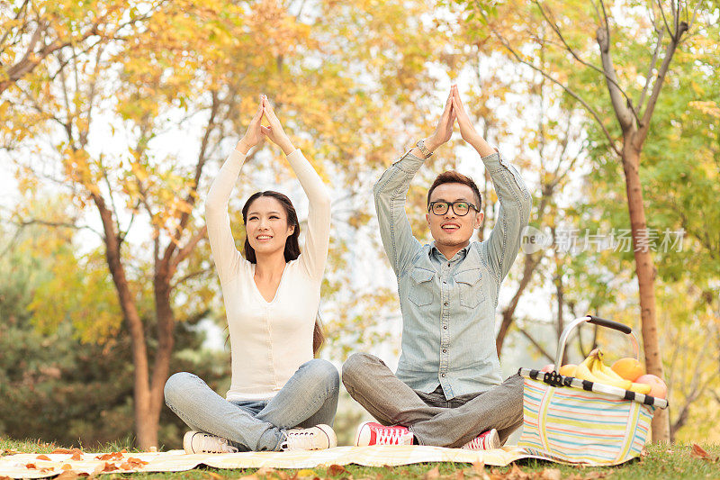 快乐的年轻夫妇在公园里练瑜伽