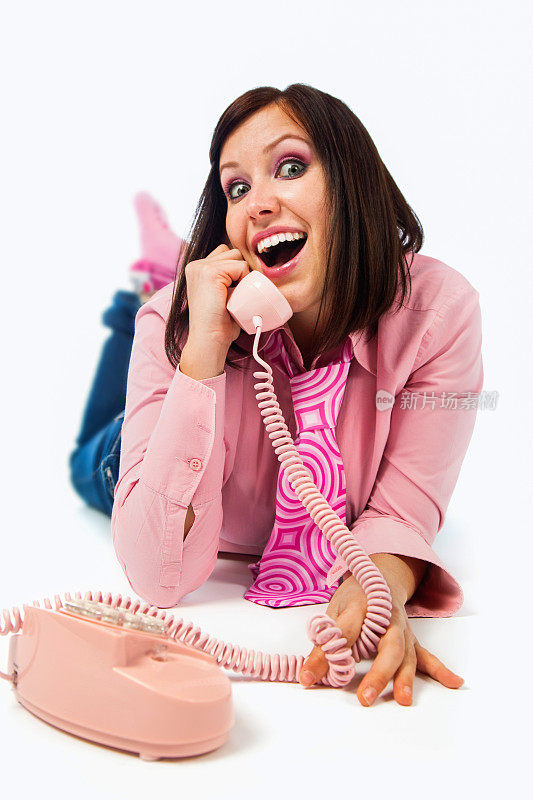 年轻的女孩在用粉红色的手机说话，面带微笑