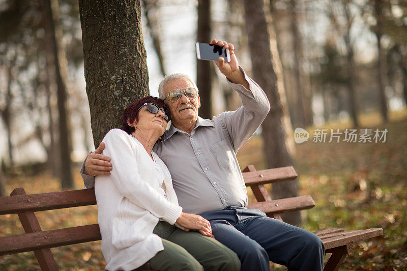 一对老年夫妇正在用智能手机拍照