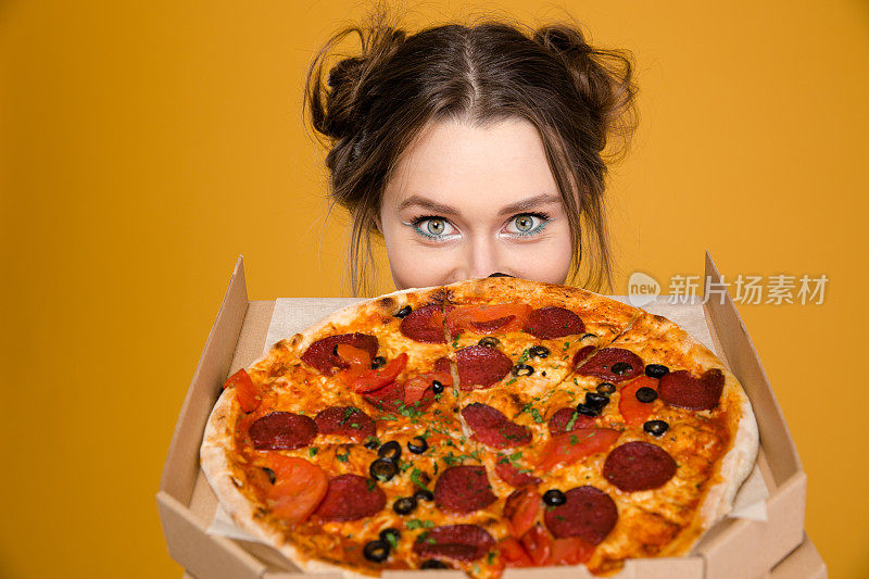 可爱可爱积极的年轻女子躲在披萨后面
