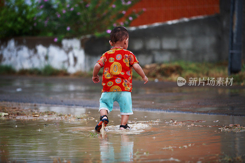 小男孩玩自由雨水水坑溅水