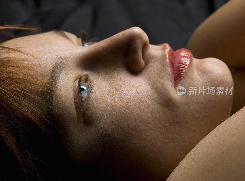 一个女人躺着，眼睛睁开的侧面视角