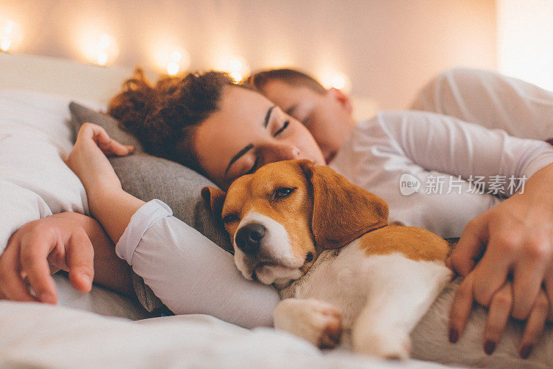 一对年轻夫妇和她的宠物狗在床上休息