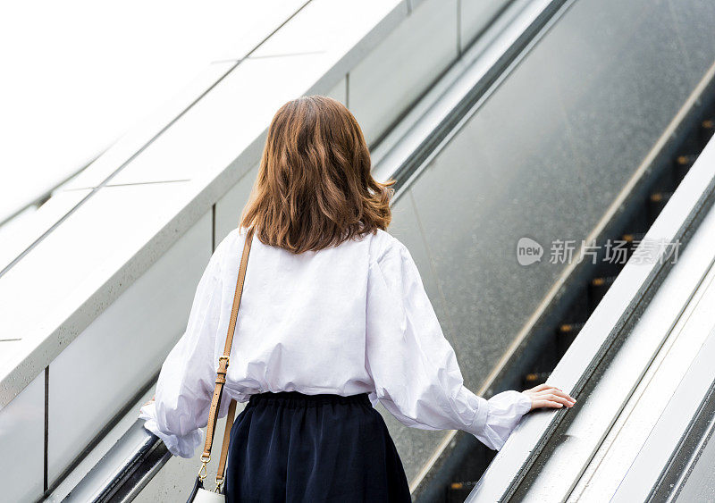 日本东京，一名女性在自动扶梯上上班