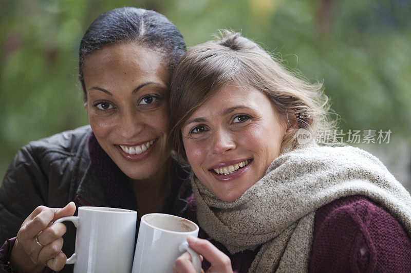 两个微笑的年轻女人拿着咖啡杯