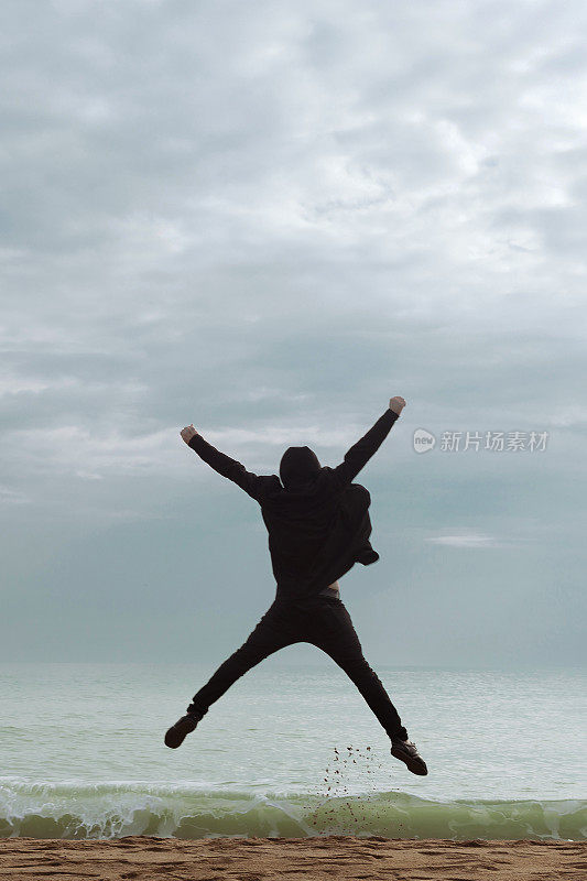 穿着黑衣服的年轻人在海滩上蹦蹦跳跳
