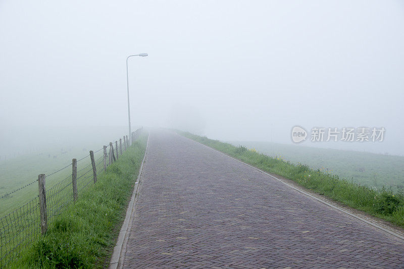 晨雾弥漫的堤岸上空无一人的道路