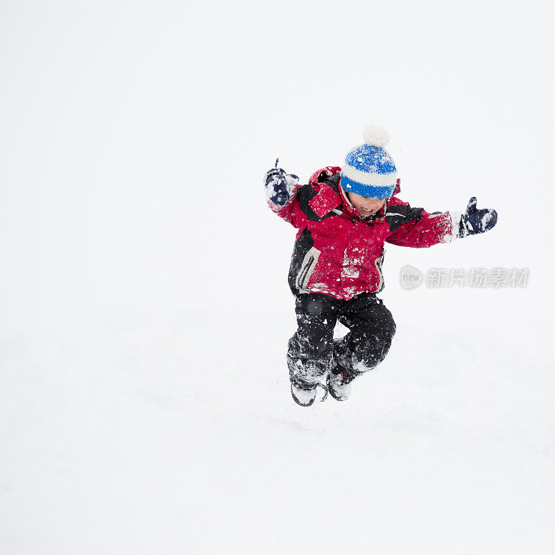 小男孩在雪中跳跃